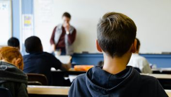 A pupil watching a teacher at the front of a classroom