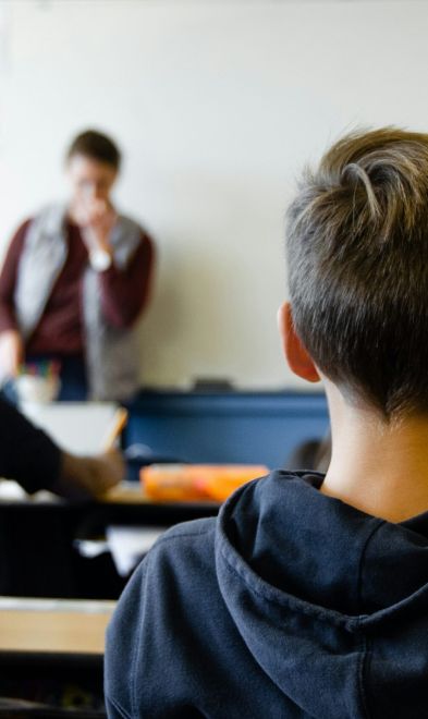 A pupil watching a teacher at the front of a classroom